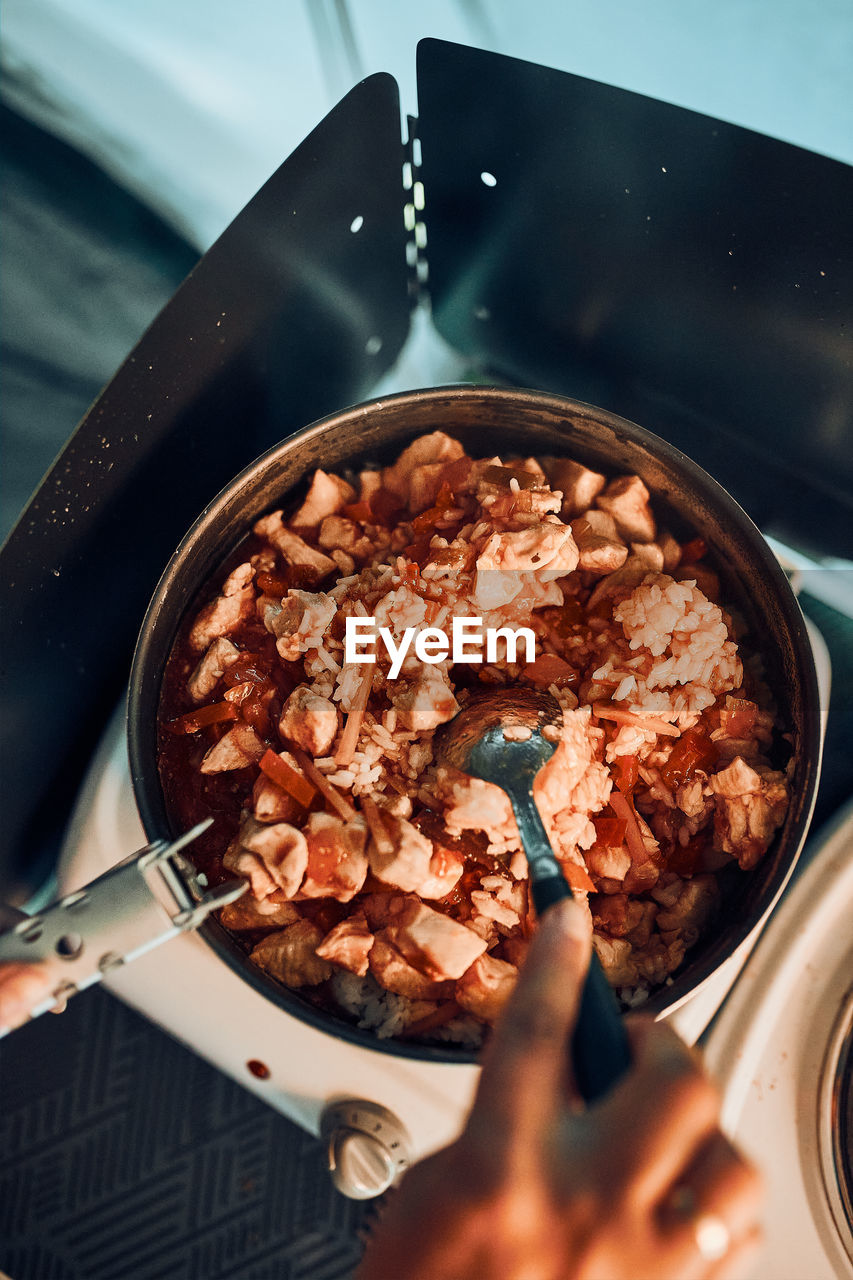 Close up of female hands putting dish with tomato sauce. woman cooking meal on electric stove