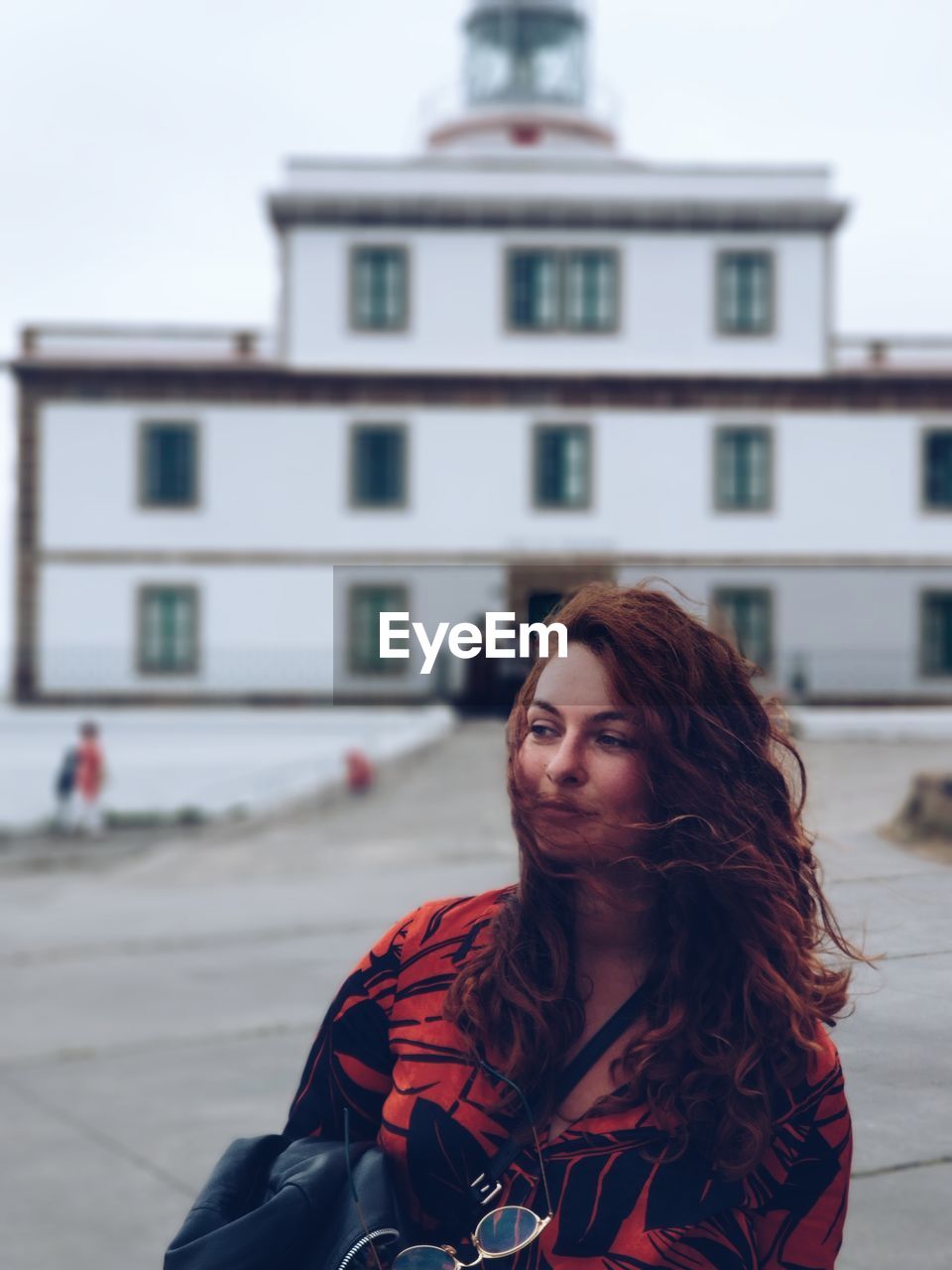 Portrait of young woman standing against lighthouse