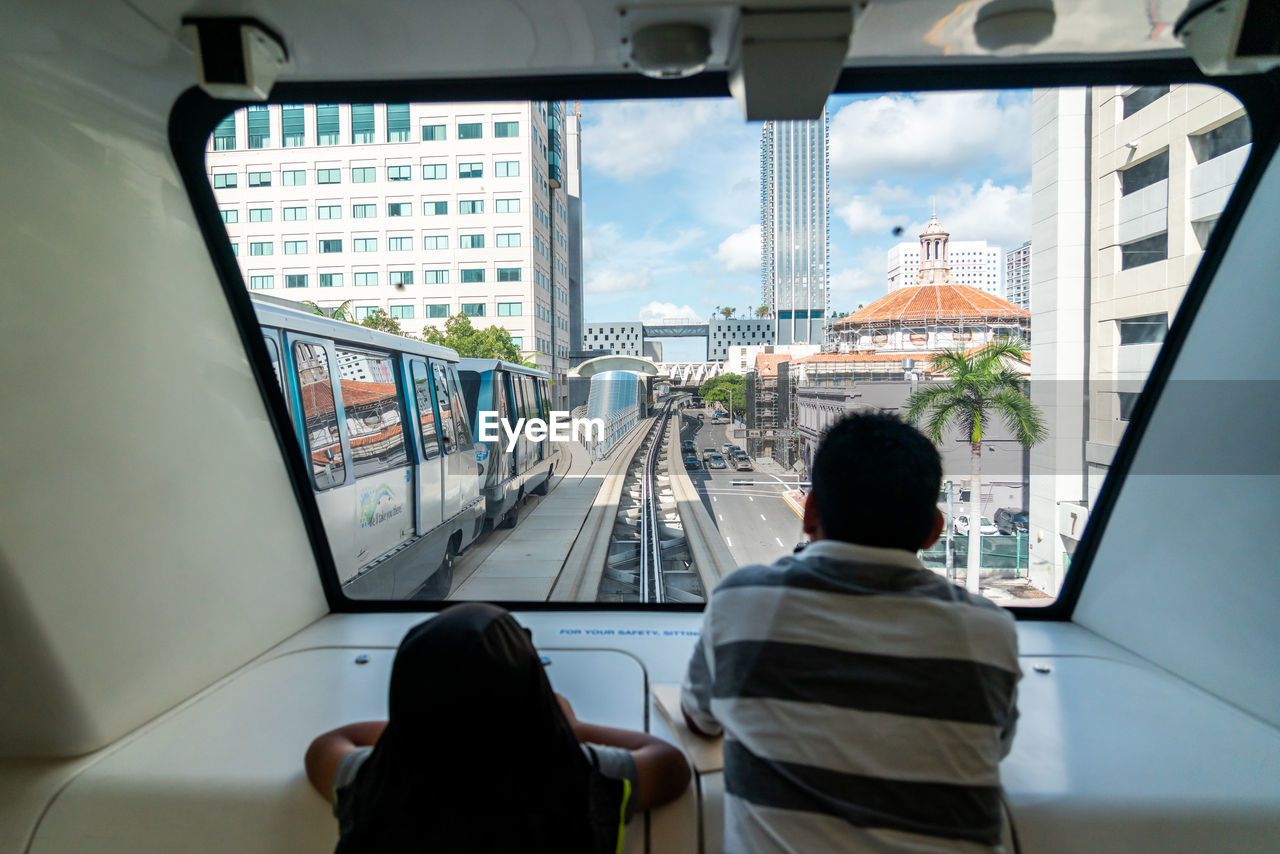 REAR VIEW OF MAN AND WOMAN IN BUS