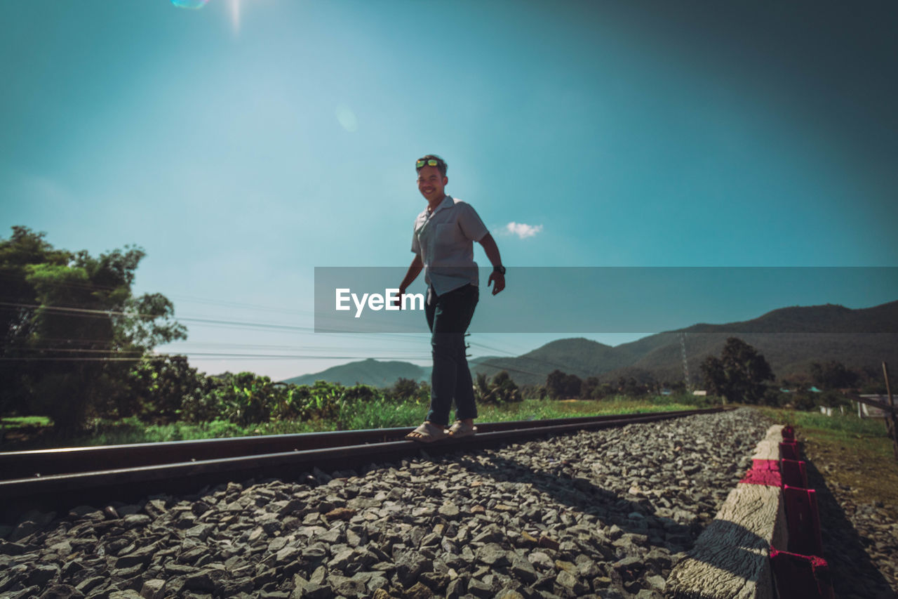Man standing on railroad track against sky