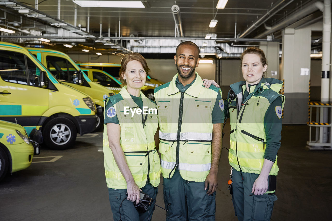 Portrait of male and female ambulance staff standing together in parking lot