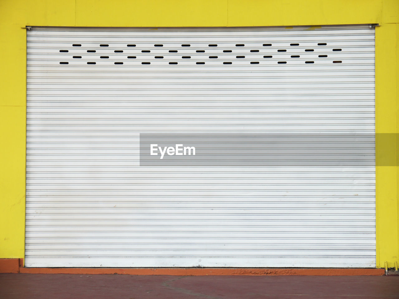 Closed shutter of yellow wall