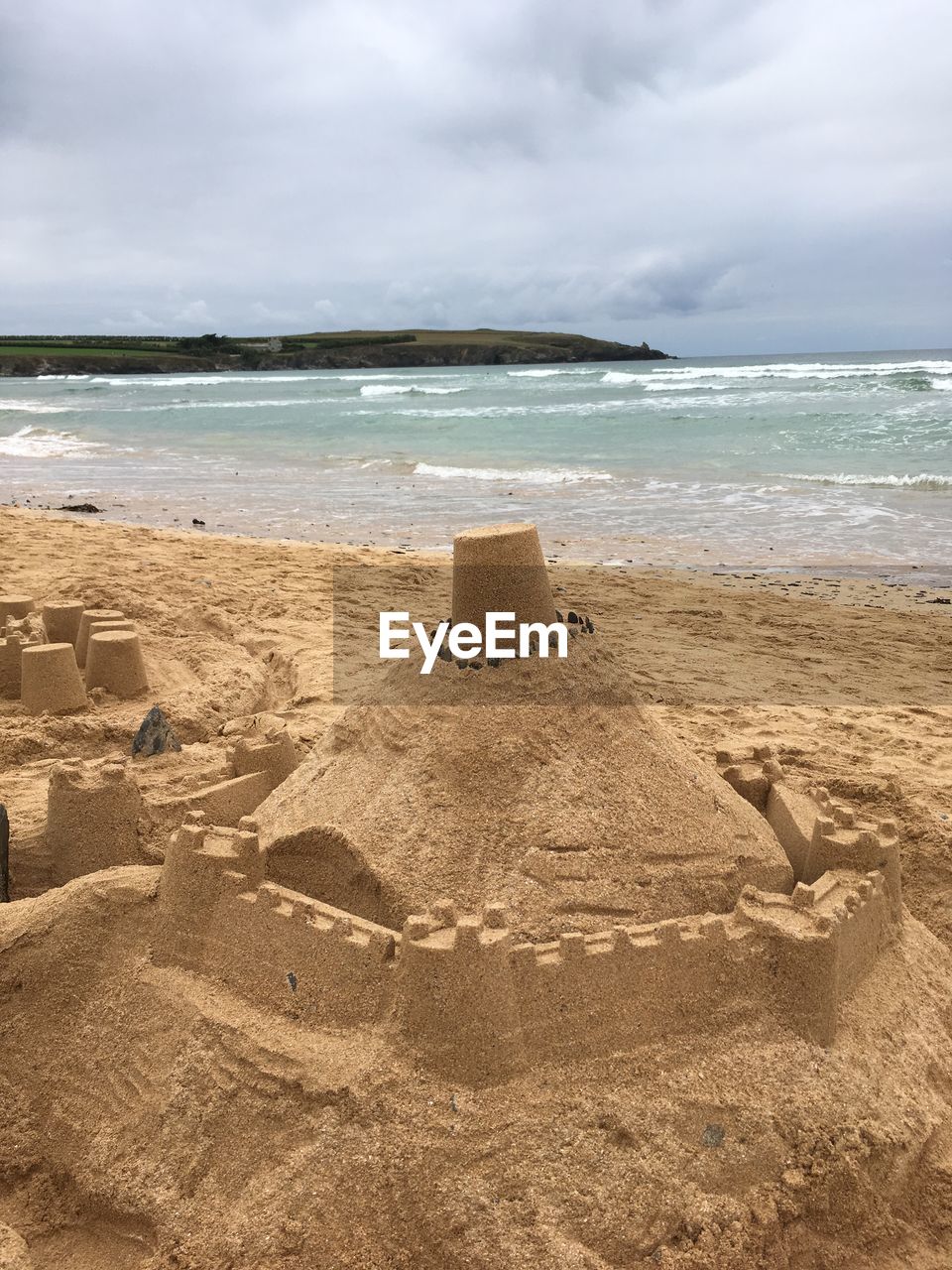 Sandcastle at beach against cloudy sky