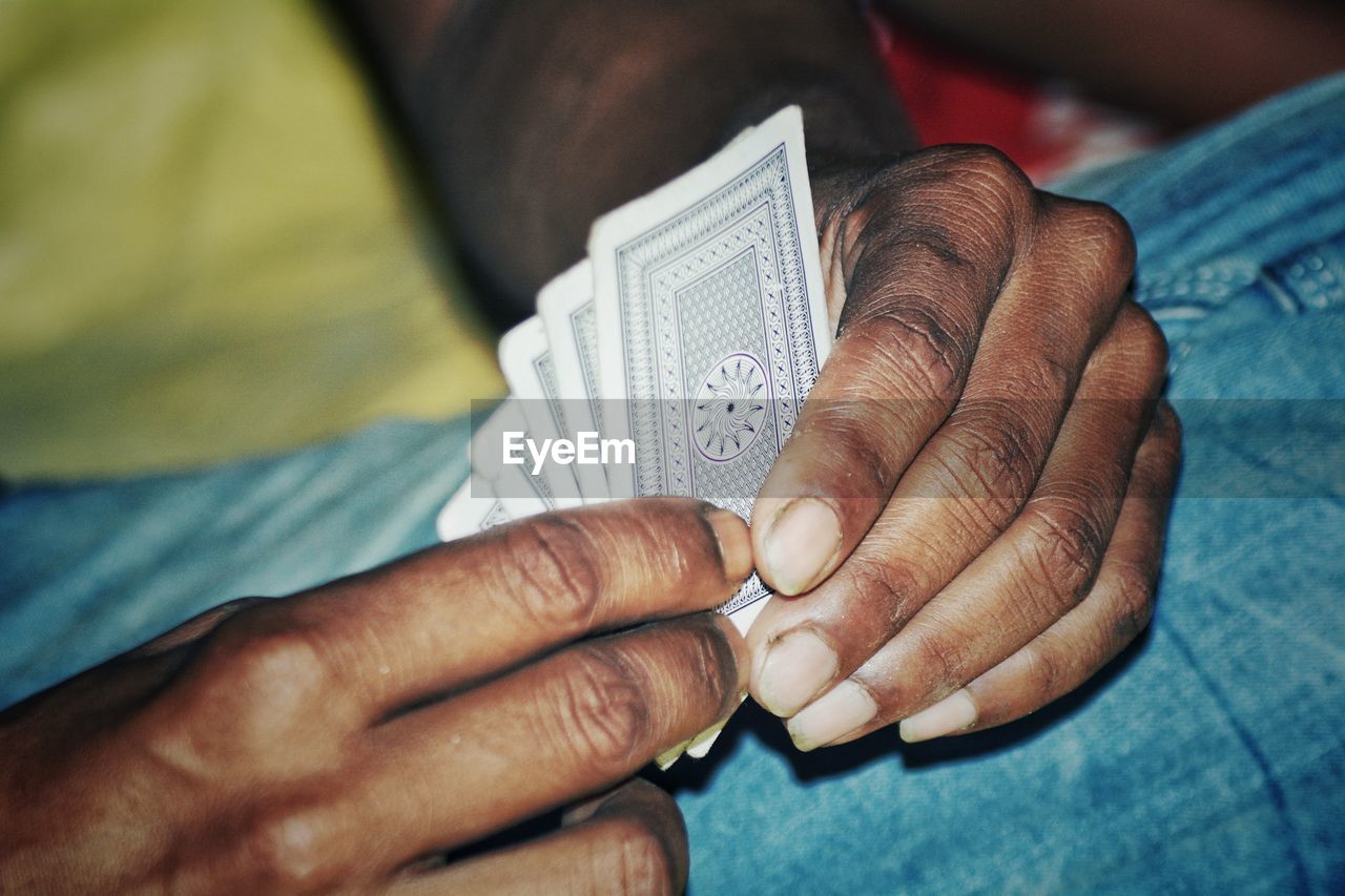Cropped hands holding playing cards at home