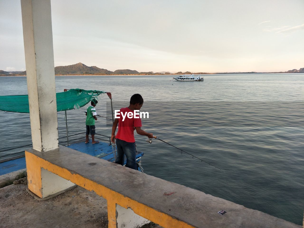 MEN FISHING ON PIER AGAINST SKY