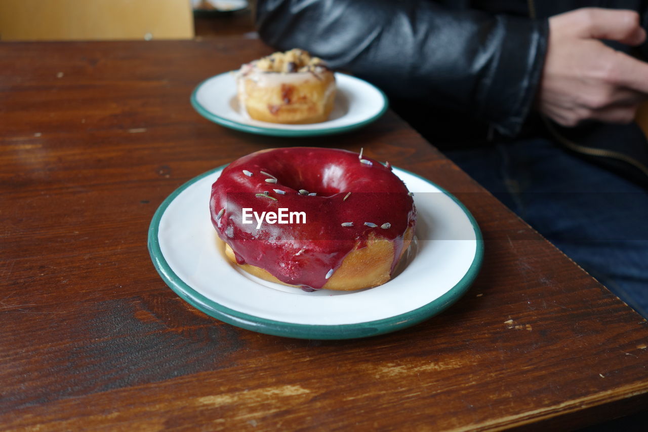 Cropped image of man with donut in plate on table