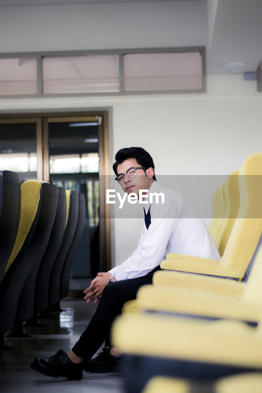 Portrait of young man relaxing on seat in office