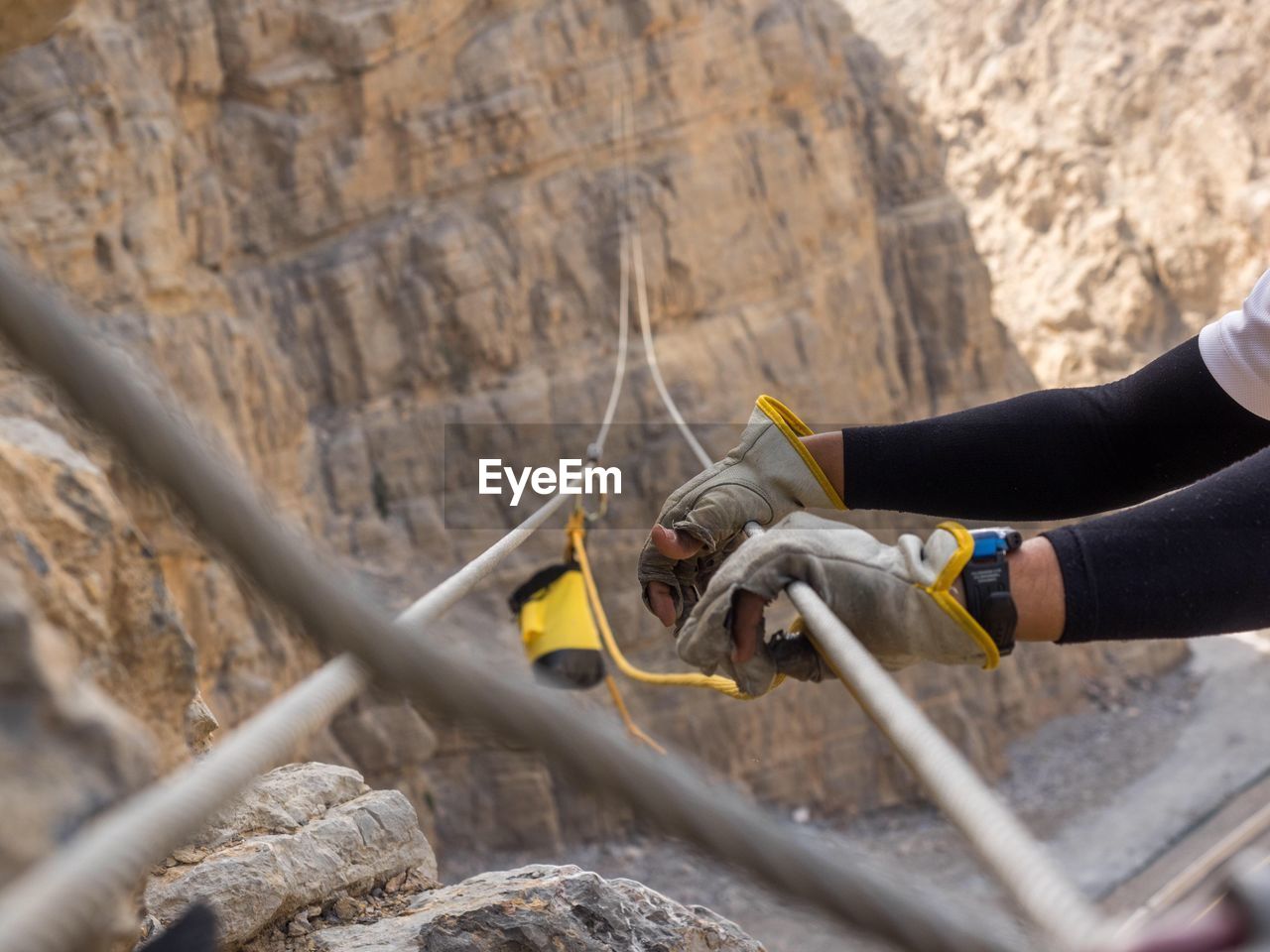 Cropped hands holding rope while climbing mountains