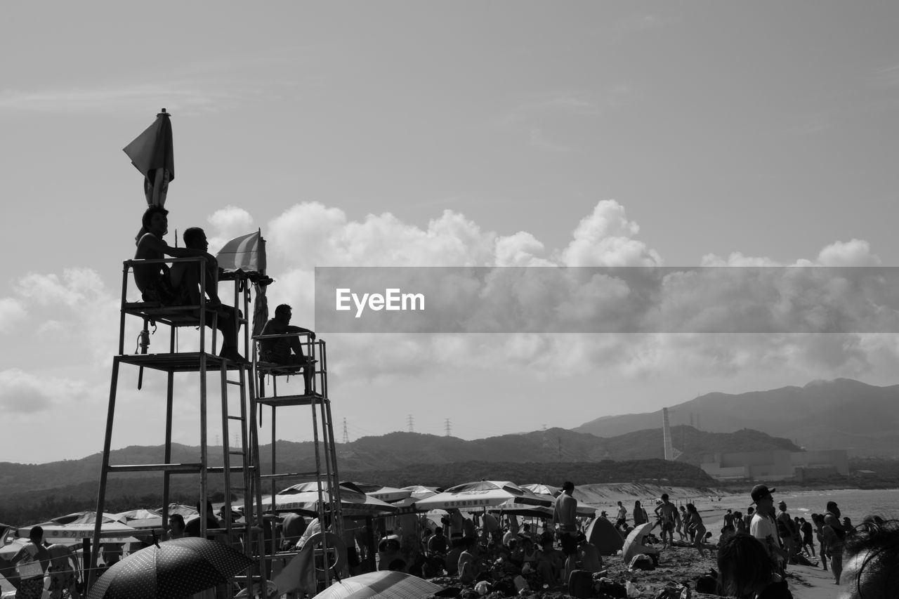 PEOPLE ON BEACH AGAINST MOUNTAINS