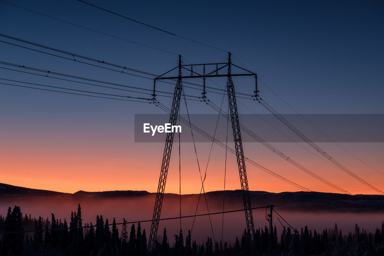 Silhouette electricity pylon against sky during sunset