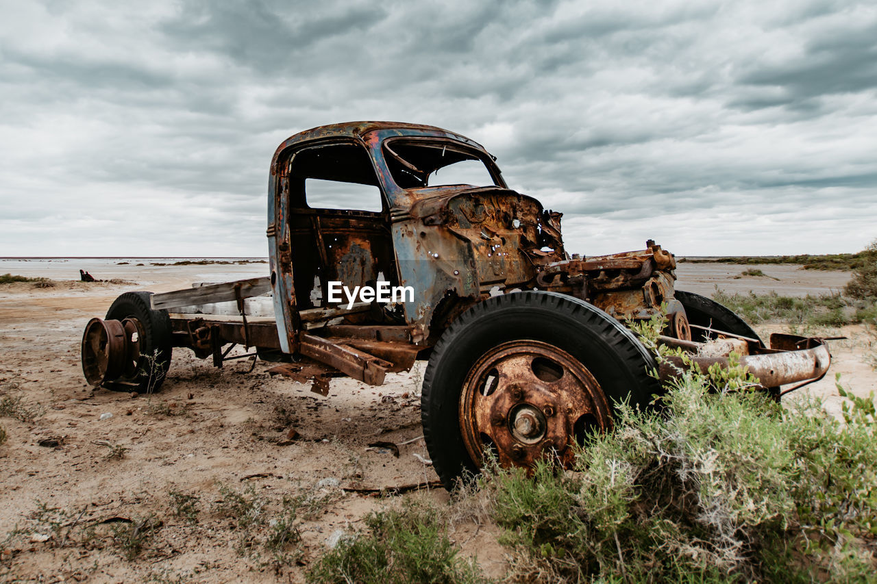 Old abandoned truck on field against sky