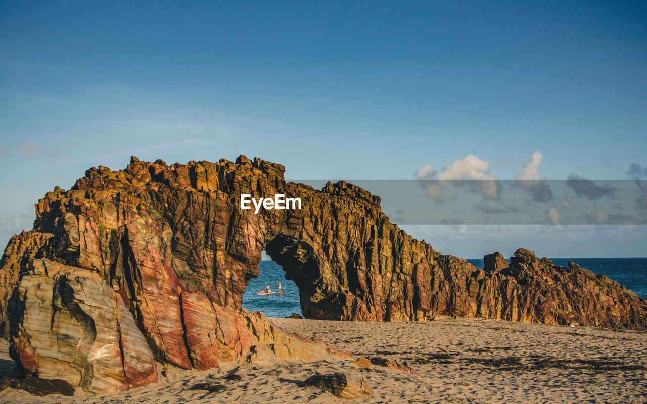 Rock formations on beach against sky