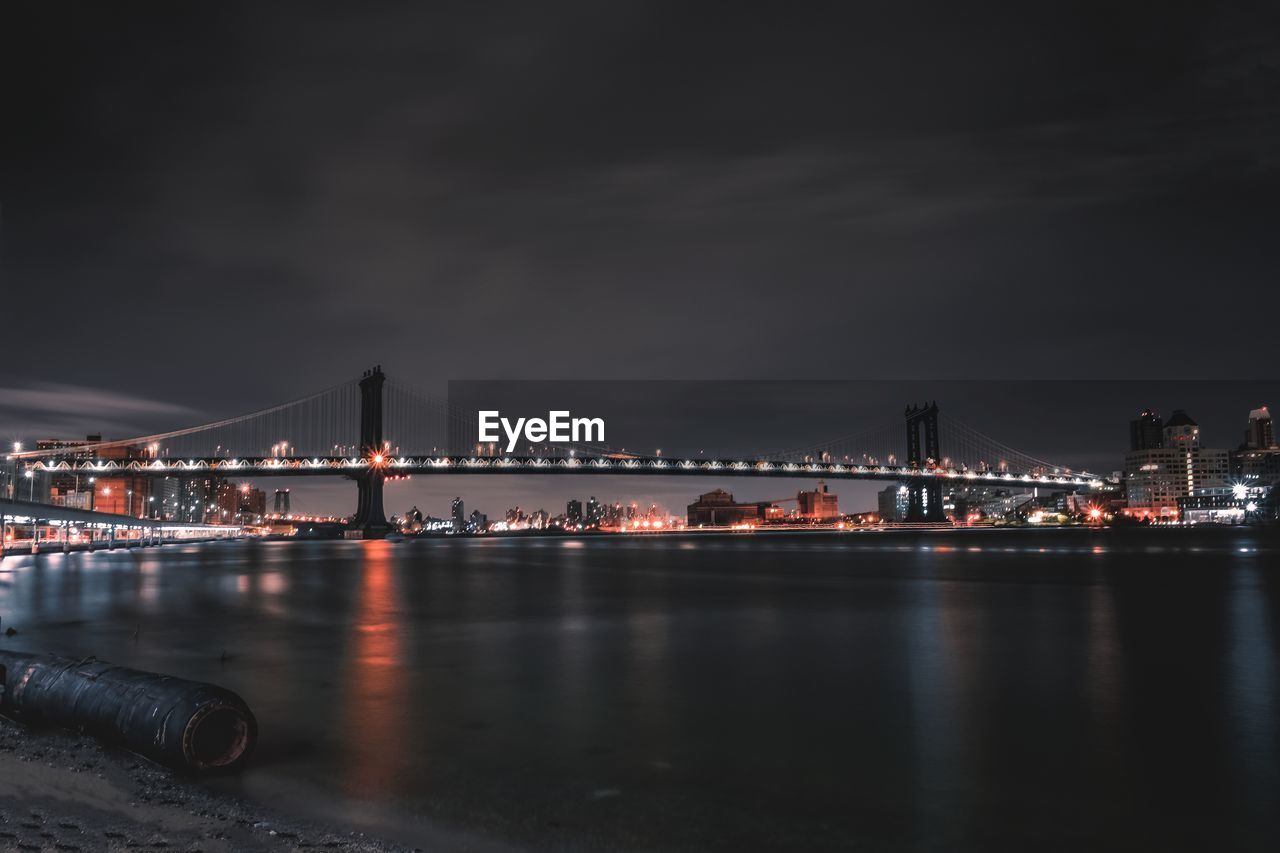 Illuminated bridge over river at night