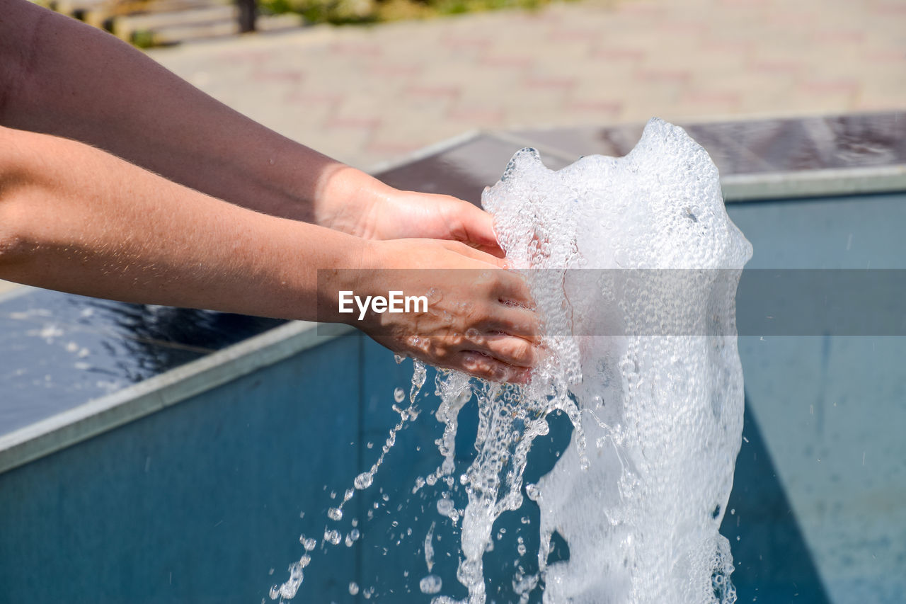 Close-up of hands splashing water at poolside