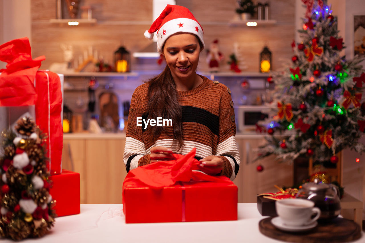 PORTRAIT OF HAPPY YOUNG WOMAN WITH CHRISTMAS LIGHTS