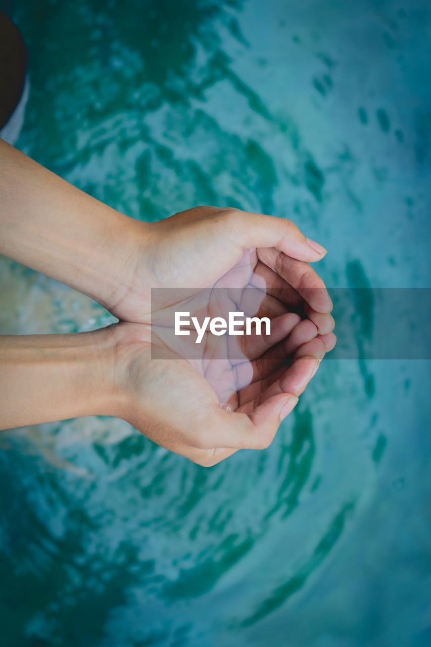 HIGH ANGLE VIEW OF PERSON HAND ON SWIMMING POOL