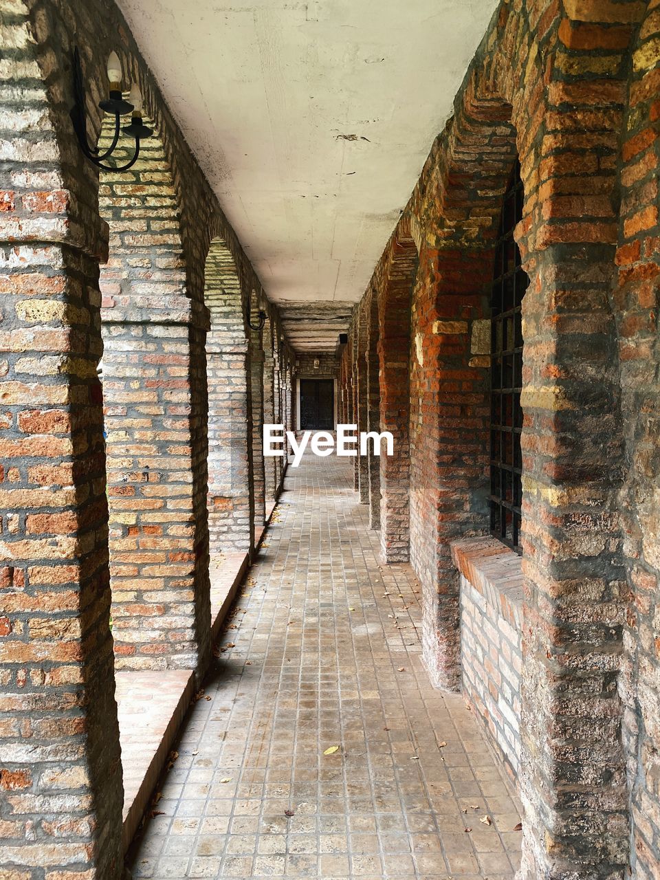 Vanishing point in an outside corridor with old brick columns and walls with no people 