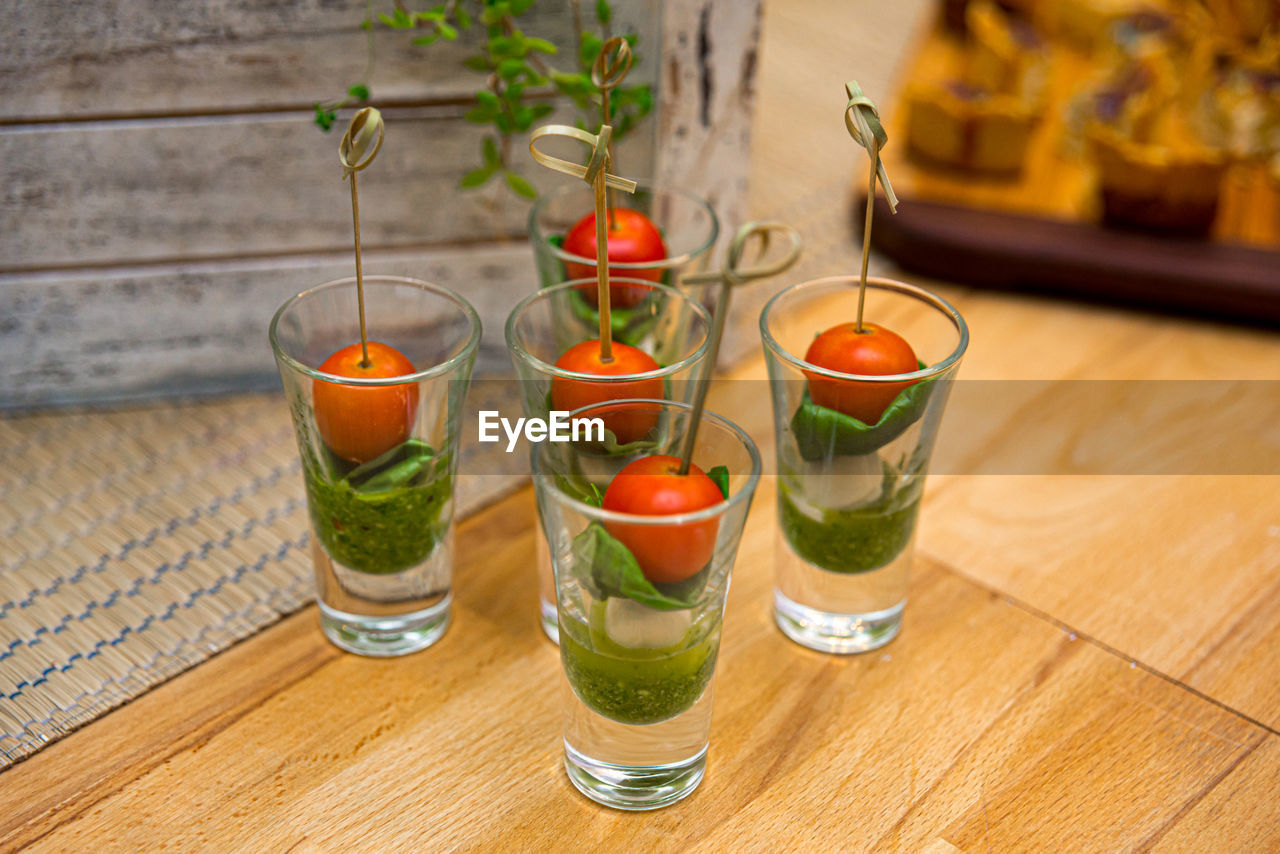 Caprese canapes in glass stacks. cherry tomatoes, mini mozzarella balls, pesto sauce.