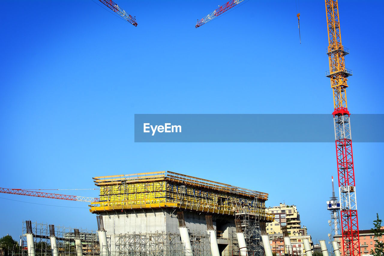 LOW ANGLE VIEW OF CRANE AGAINST BLUE SKY