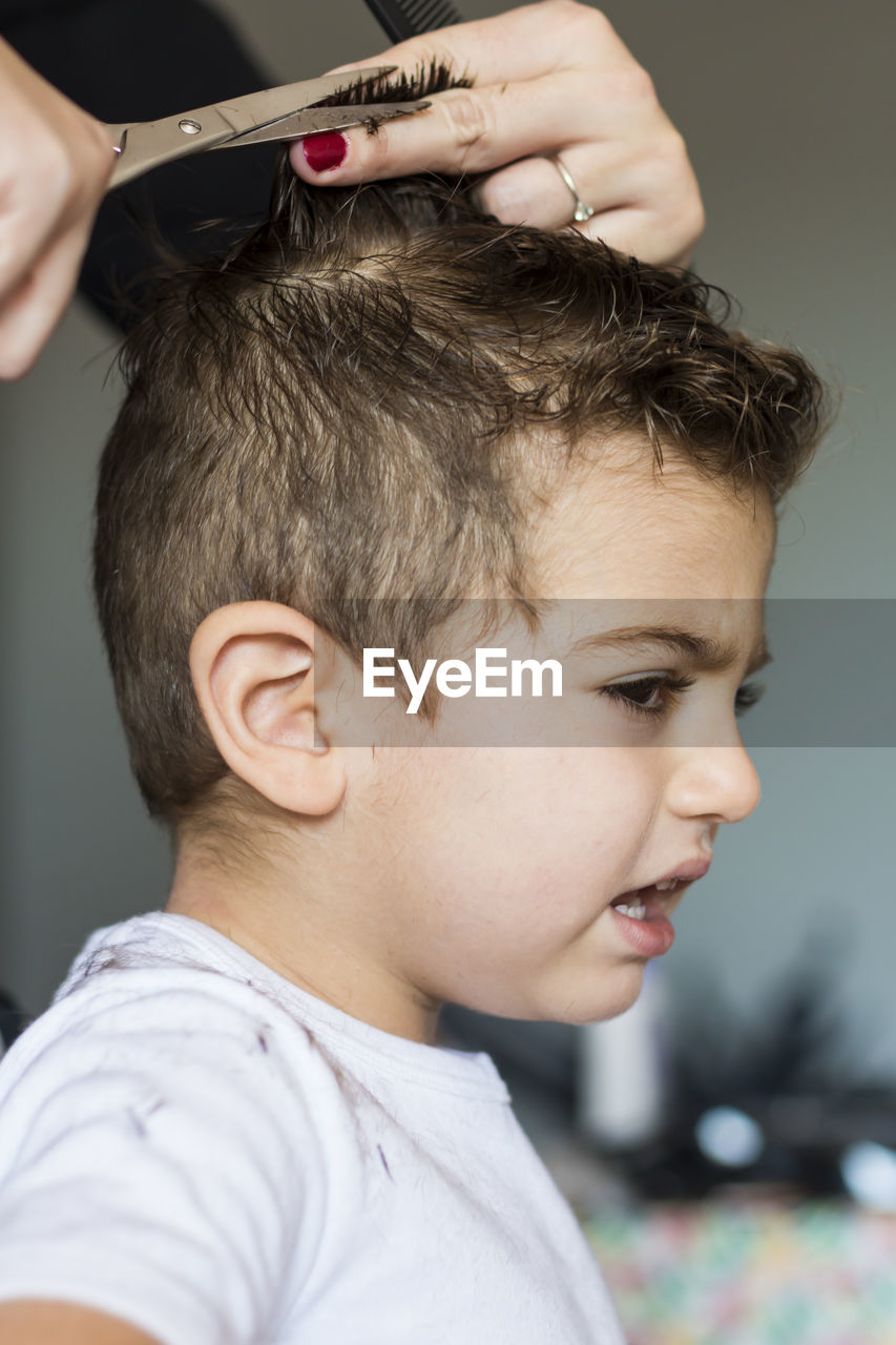 Cropped hands of hairdresser cutting boy hair