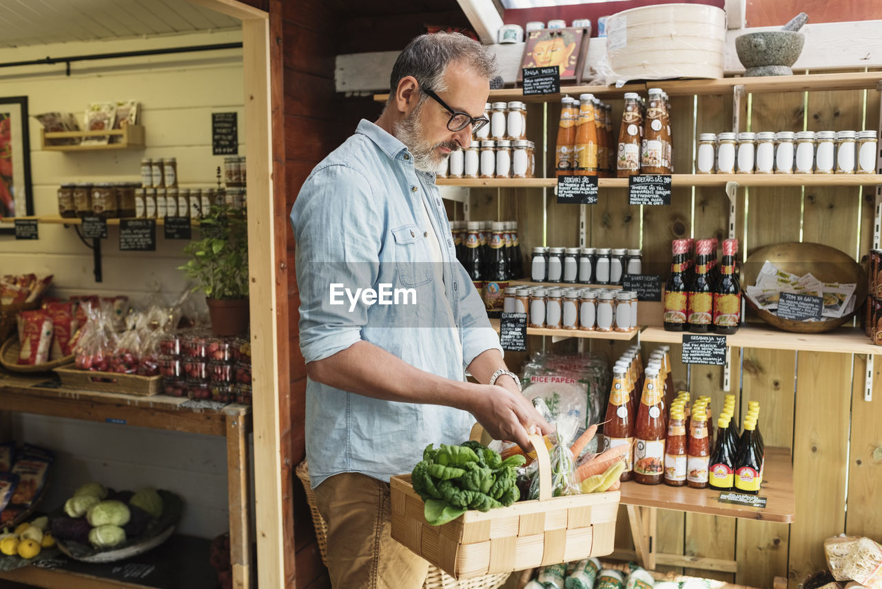 Mature man carrying basket while shopping in food store