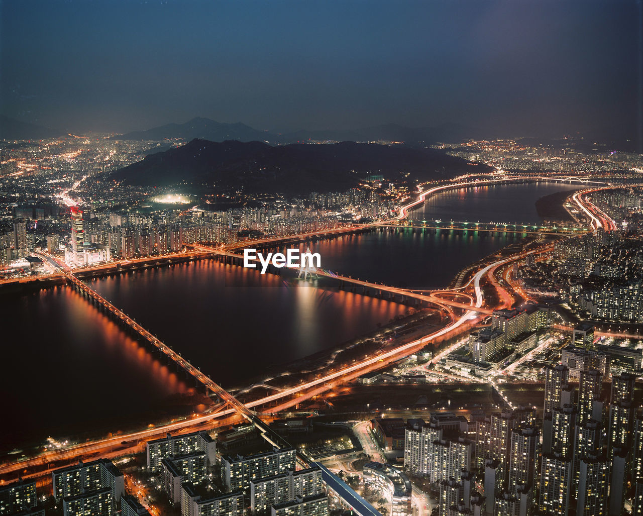 High angle view of city and suspension bridge at night