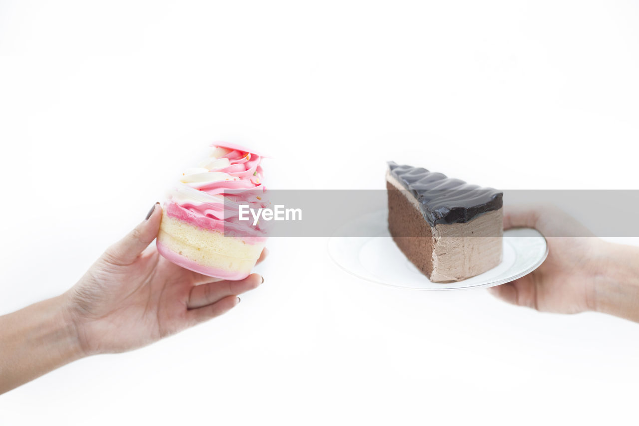 MIDSECTION OF PERSON HOLDING CAKE AGAINST WHITE BACKGROUND