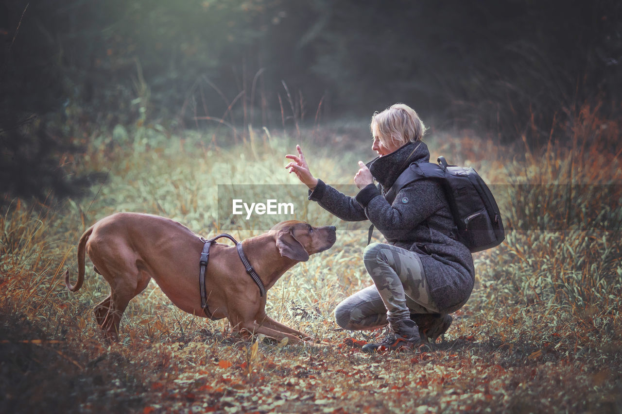 Side view of mature woman playing with dog on field