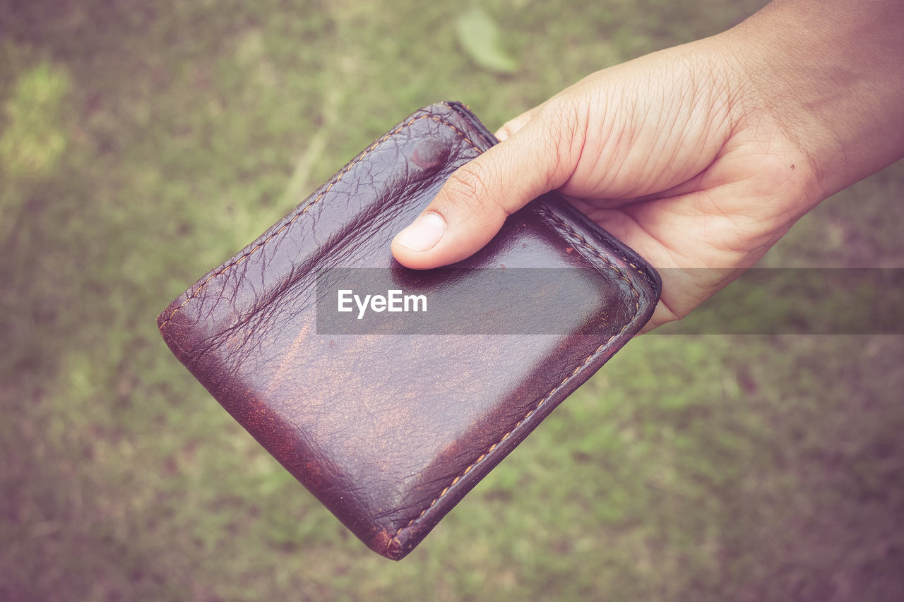 Close-up of person holding wallet outdoors