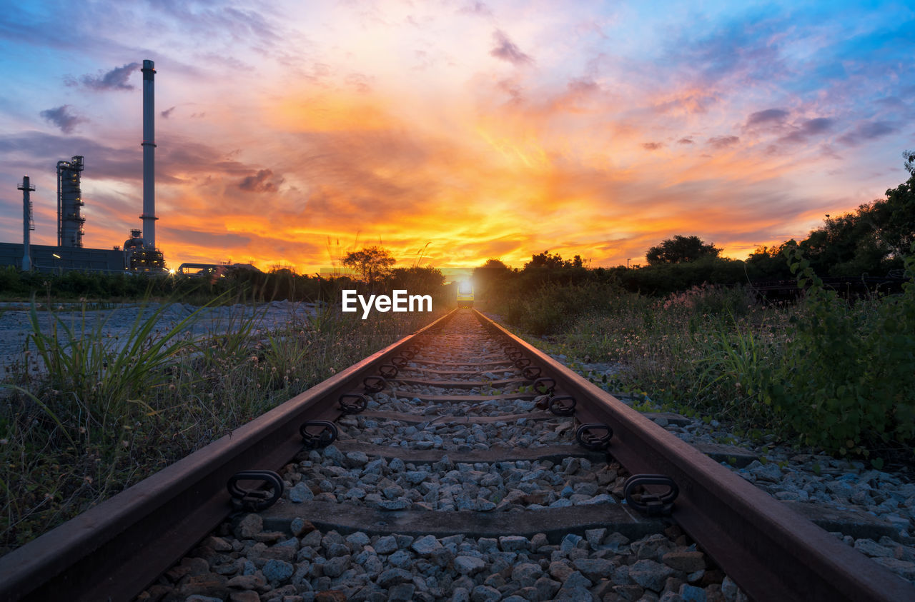 SURFACE LEVEL VIEW OF RAILROAD TRACKS AGAINST SKY DURING SUNSET