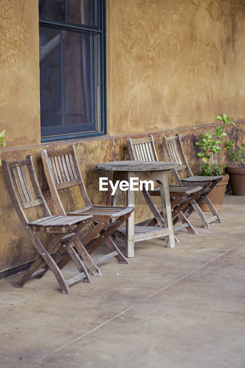 EMPTY CHAIRS AND TABLE OUTSIDE HOUSE