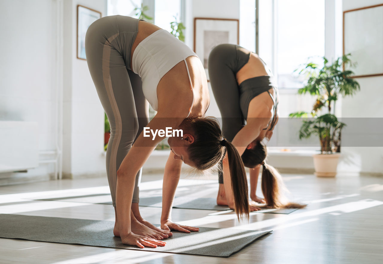 Young fit women practice yoga doing asana in bright yoga studio