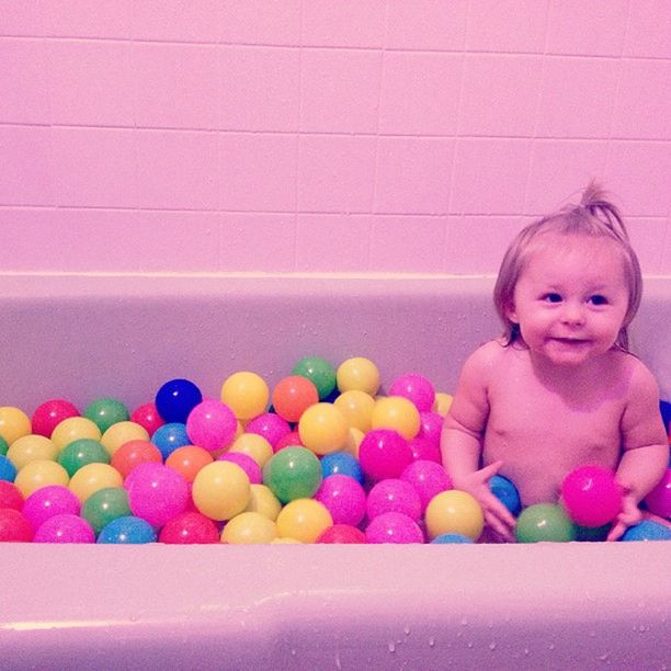 Smiling girl with colorful balls in bathtub