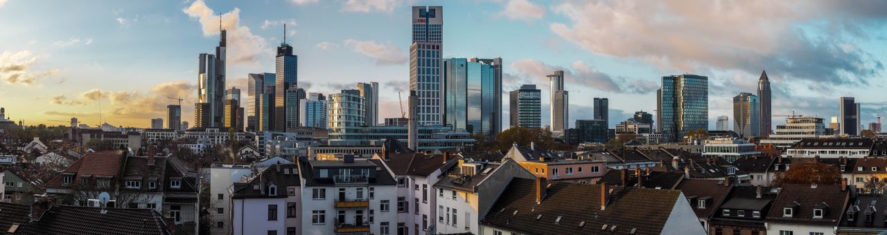 Panoramic view of buildings in city against cloudy sky