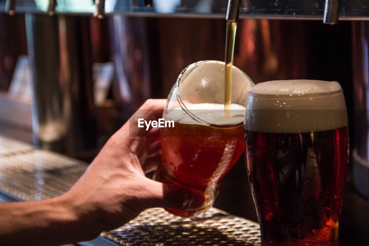 Close-up of person holding beer glass on table