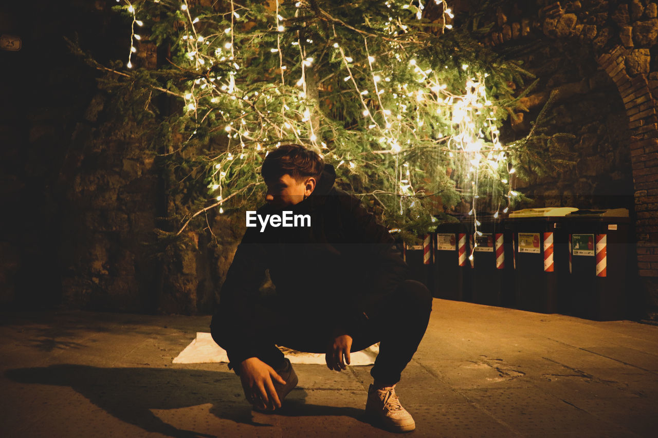 Full length of young man looking at camera at night