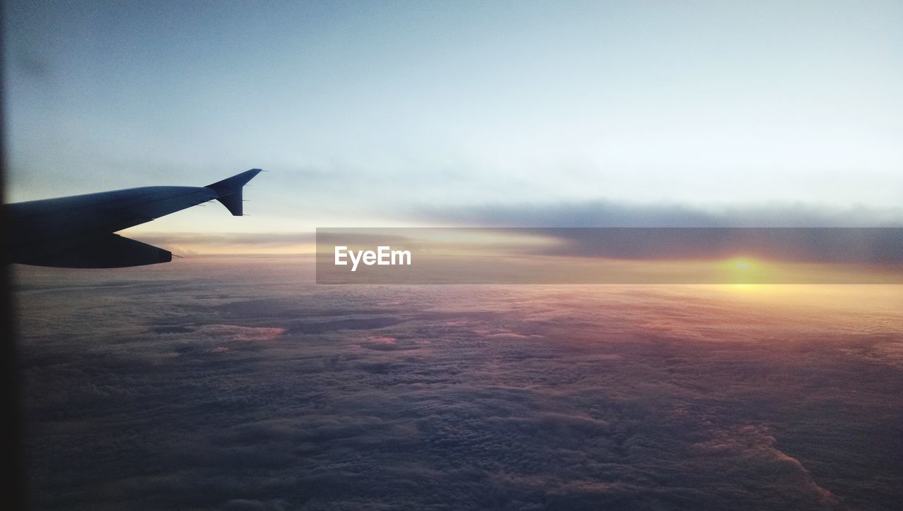 AIRPLANE FLYING OVER CLOUDSCAPE AGAINST SKY