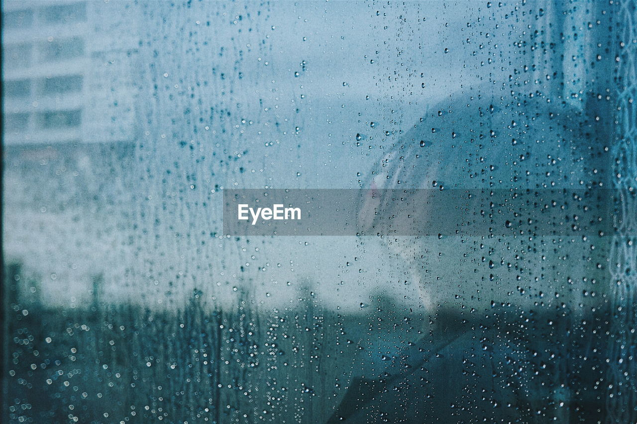 Side view of woman reflecting on wet mirror during rainy season