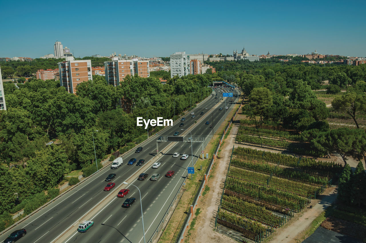 Multi-lane highway with heavy traffic in the midst of trees and buildings in madrid, spain.