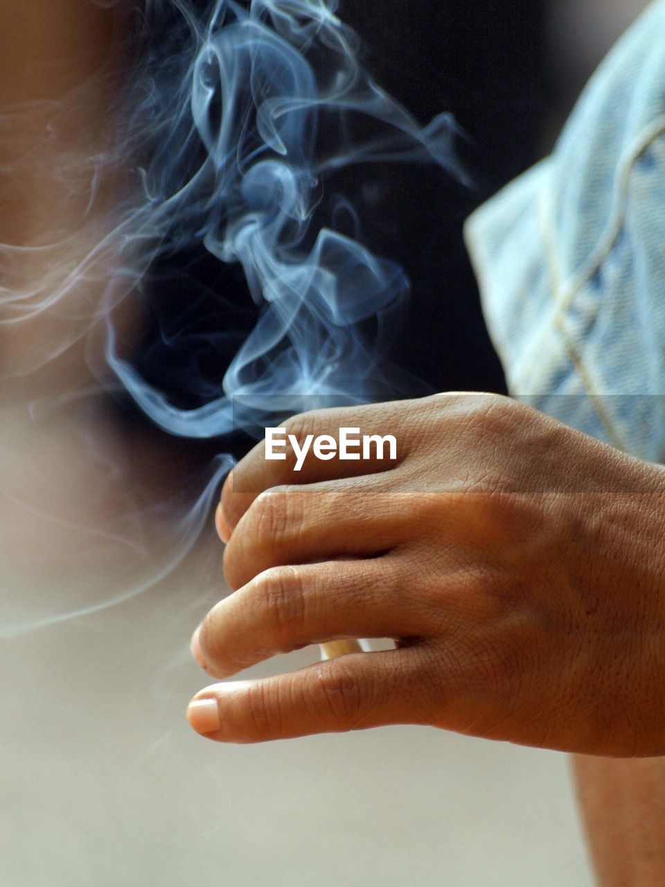 Close-up of human hand holding burning cigarette outdoors