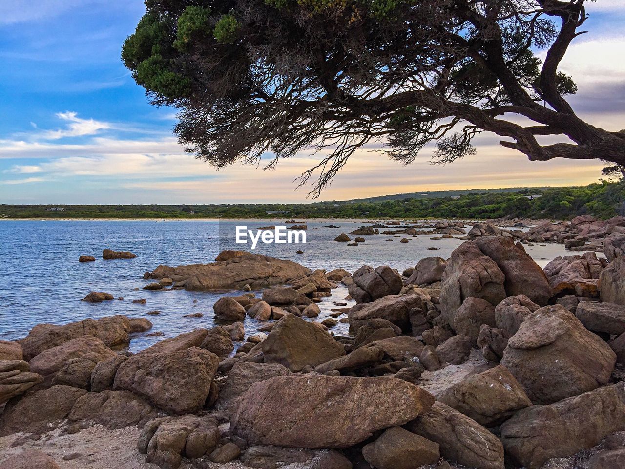 Scenic view of rocky shore against sky at sunset