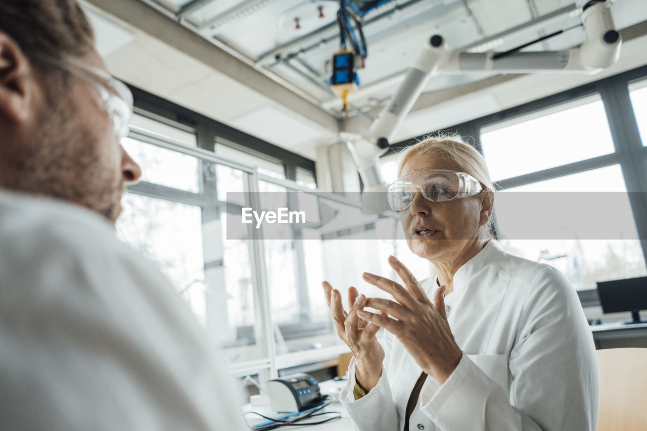 Senior scientist explaining to colleague in laboratory