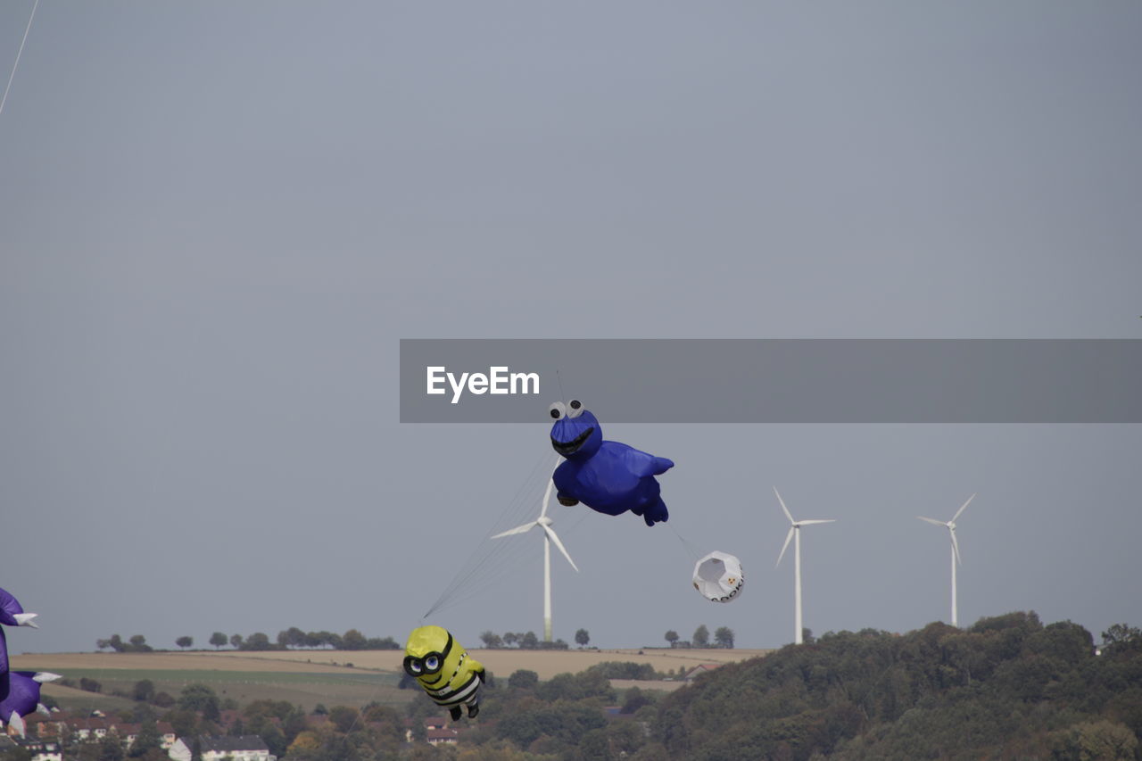 PEOPLE PARAGLIDING AGAINST SKY