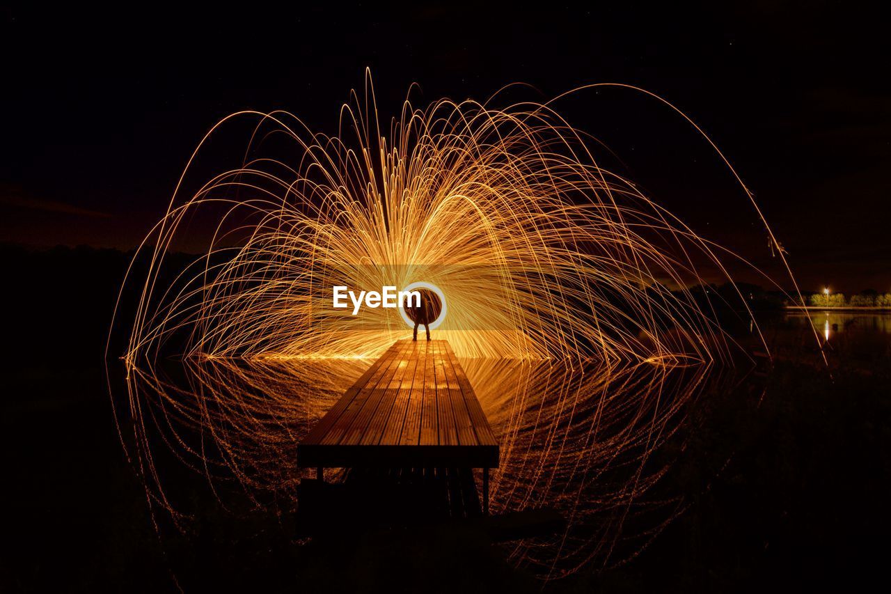 Person spinning wire wool on pier