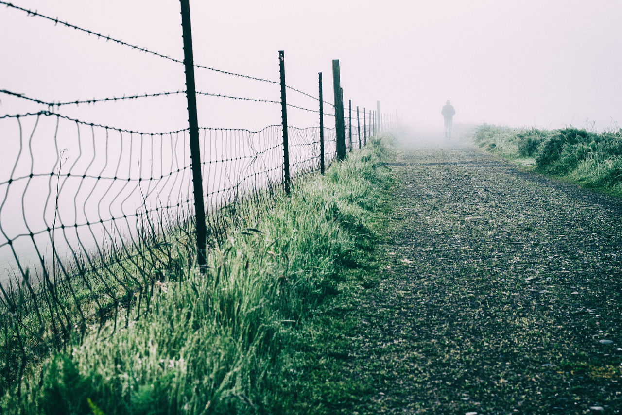 Silhouette of man walking along footpath in fog