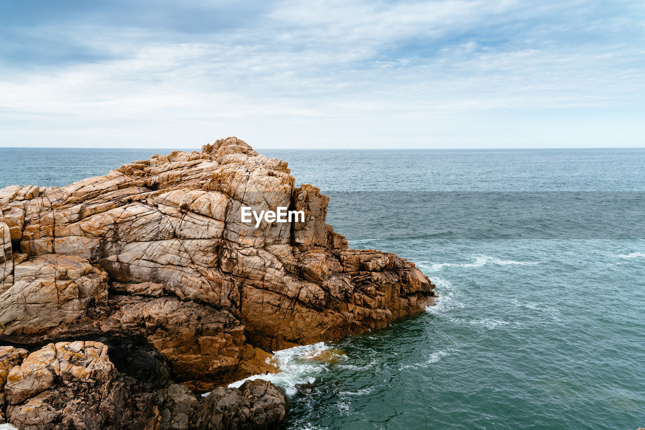 Rock formation in sea against sky