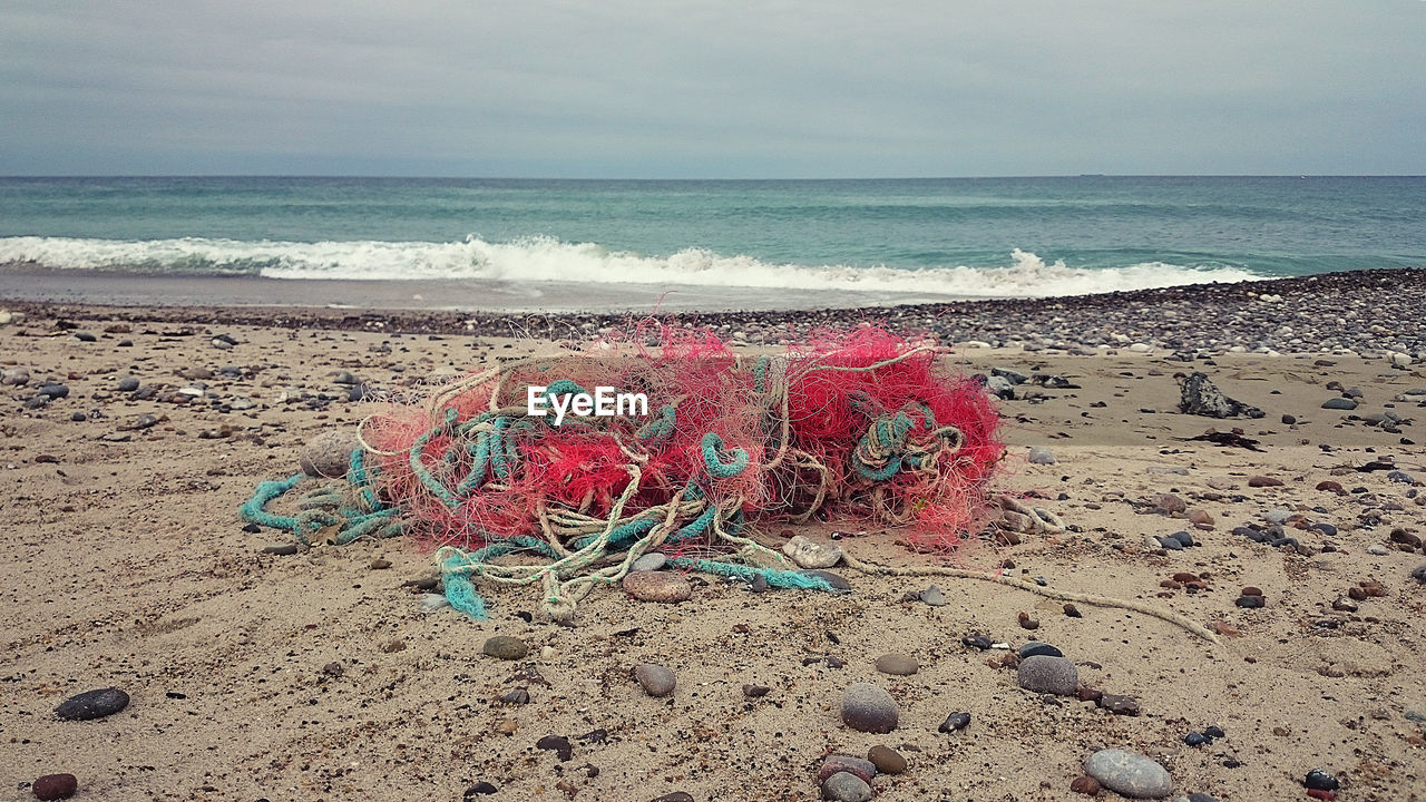 Fishing net on beach against sky