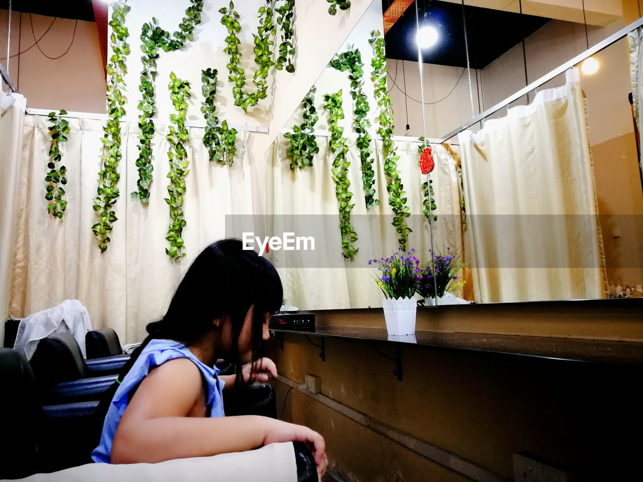 WOMAN SITTING BY PLANTS AT HOME