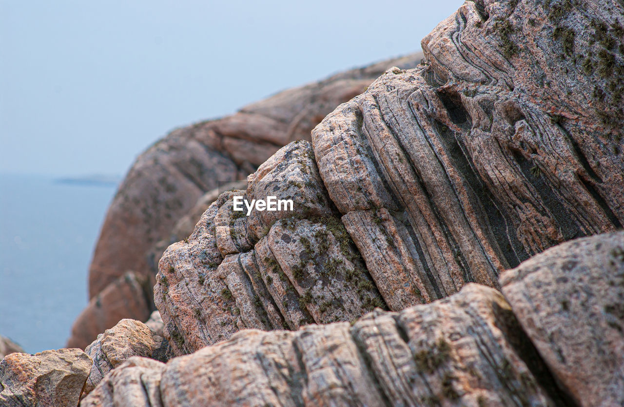 CLOSE-UP OF ROCKS ON ROCK AGAINST SEA