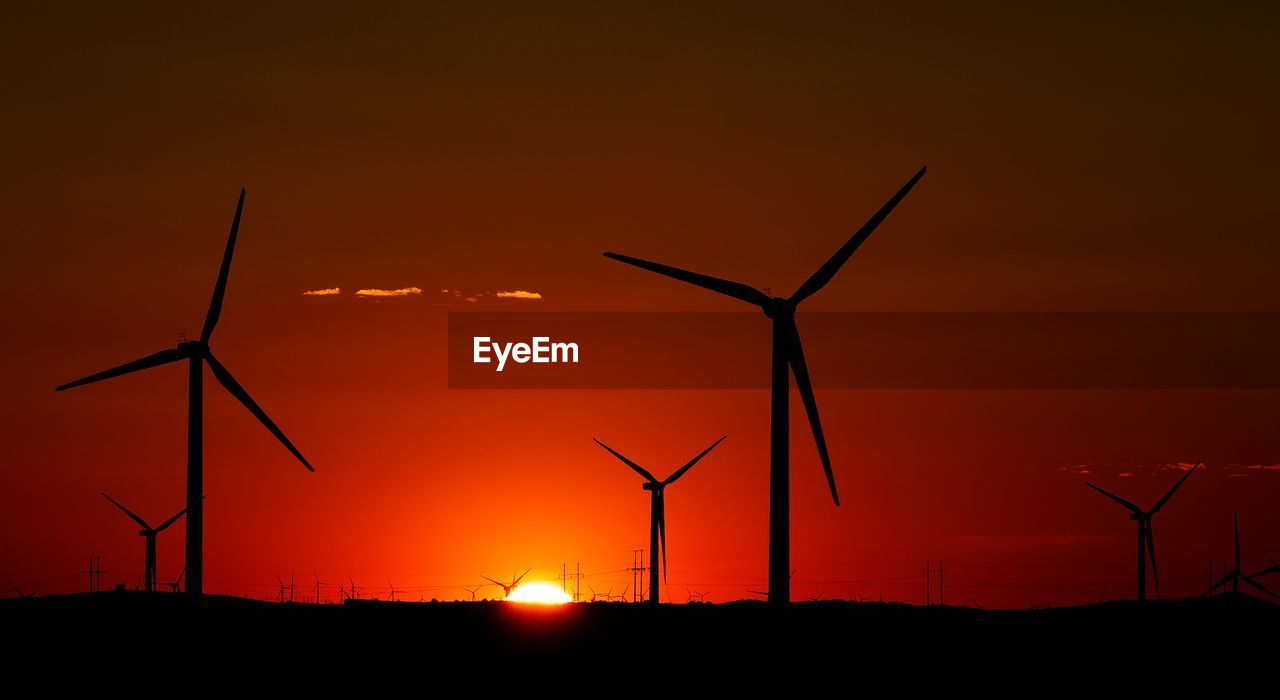 Silhouette windmills against sky during sunset